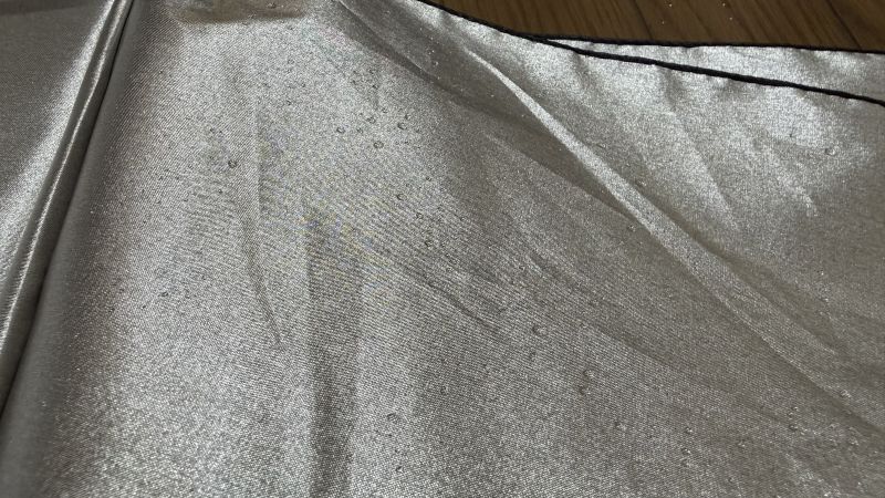 水をバサバサと払った後の生地表面。国産の高性能傘のように水滴が転がり落ちず、細かい水滴が全体に滲むように残っている。