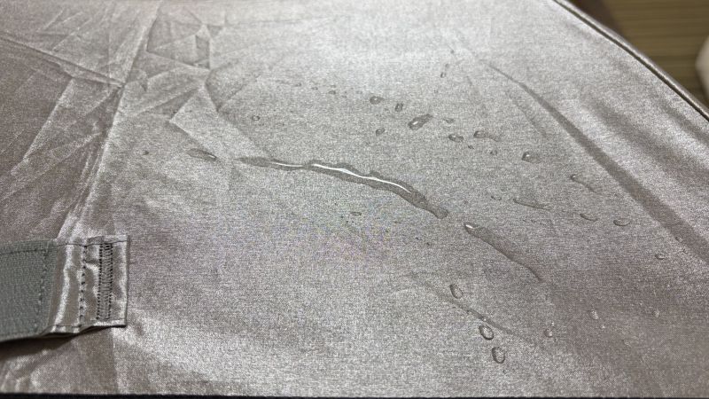 残った水を指で伸ばした様子。水は玉にならず、シルバー生地の織り目に沿って完全に広がっている。