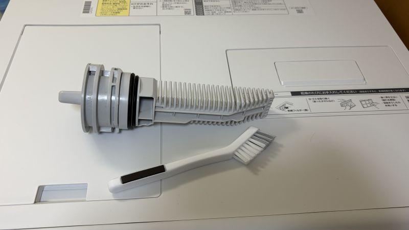 洗濯機の排水フィルターと、100円ショップで購入した磁石付き掃除用ブラシ。細かい部分も洗いやすい山型の毛先。