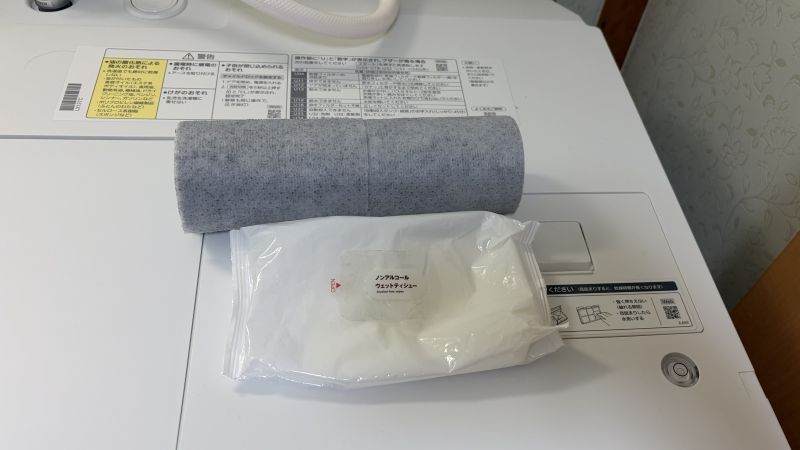 洗濯機の上に置かれた、無印良品の「水回りの汚れ用掃除シート」とウェットティッシュ。日々のお手入れに便利なアイテム。