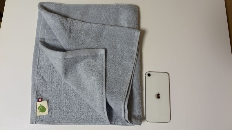 洗濯前のエアーかおる・旧タイプ（半分サイズ）の「わたのはなNo.2」（フォグ）とiPhoneSEを並べたサイズ比較写真