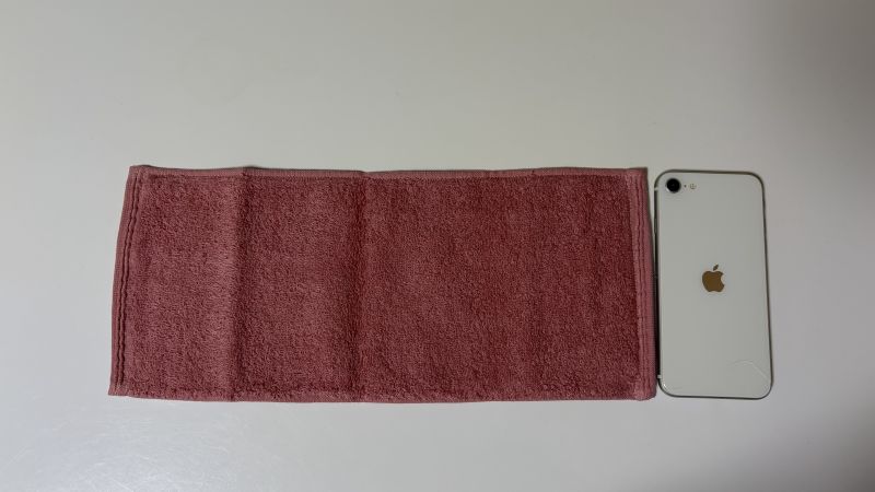 洗濯前のエアーかおる・なでしこハンカチタオルとiPhoneを並べた大きさ比較